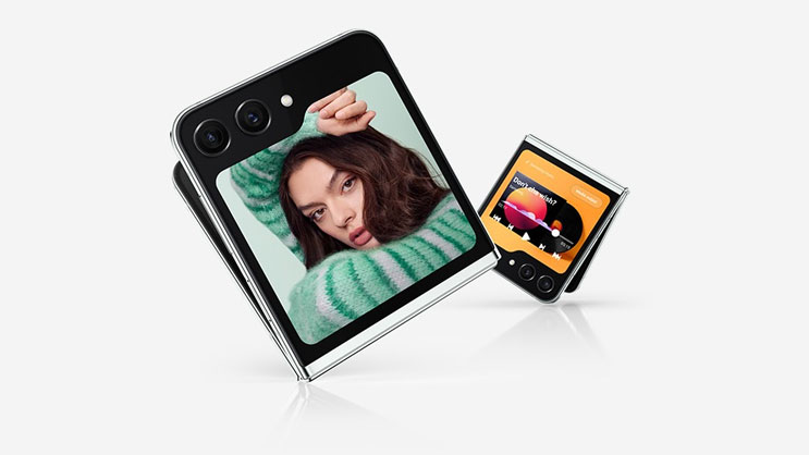 Two Galaxy Z Flip5 devices are slightly unfolded and seen from the Cover Screen. One shows a Rear Cam selfie. The second shows an expanded media player with playback controls and a progress bar.